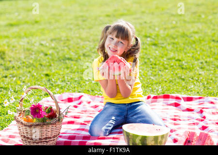 niedliche kleine Mädchen essen Wassermelone auf dem Rasen im Sommer Stockfoto