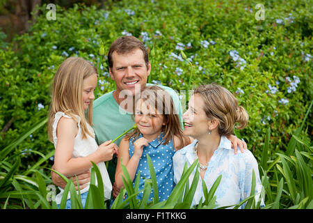 Vierköpfige Familie unter den grünen Pflanzen Stockfoto
