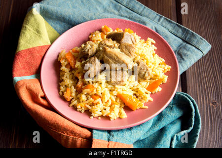 Reis-Pilaw mit Lammfleisch und Gemüse auf Holztisch und Serviette hautnah Stockfoto