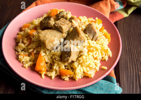 Reis-Pilaw mit Lammfleisch und Gemüse auf Holztisch und Serviette hautnah Stockfoto