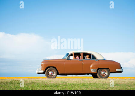 VARADERO, Kuba - 7. Juni 2011: Klassische amerikanische Oldtimer Laufwerke flach Küstenstraße vor einem tropischen Himmel. Stockfoto