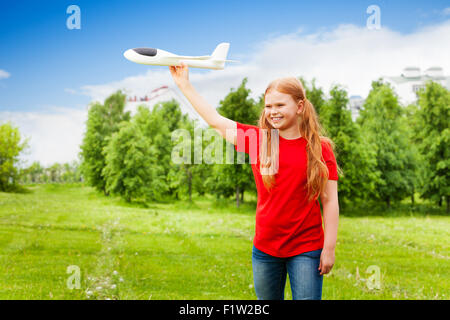 Glückliches Mädchen mit roten Haaren hält Flugzeug Spielzeug Stockfoto