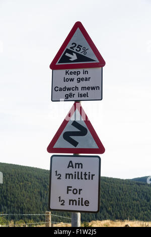 Vereinigtes Königreich dreieckigen Straße Warnung Zeichen in Wales, Platten in Englisch und Walisisch. Steil bergab auf 25 % und doppelte Biegung für ha Stockfoto