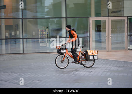 Ein TNT Postbote liefert Post an eine Adresse in Medien Stadt Manchester. Stockfoto