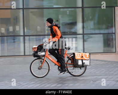 Ein TNT Postbote liefert Post an eine Adresse in Medien Stadt Manchester. Stockfoto