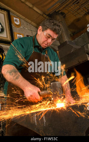 Schmied Simon Grant-Jones Hämmern heiße Metall mit Funken fliegen, in seiner Schmiede, wo er ein Handwerker-metalworker.a UK ist Stockfoto