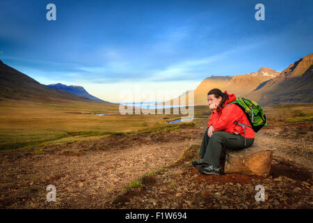 Frau nimmt eine Pause von einer langen Wanderung im Tal Seydisfjordur Fjord in Island Stockfoto