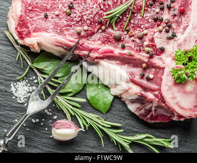 Rohes Rindersteak mit Gewürzen auf dem schwarzen Schneidebrett. Stockfoto