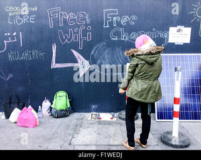 Budapest, Ungarn. 07. Sep, 2015. Eine Frau steht vor einer Tafel, die "Free Wifi" und "Kostenlose Ladestation" am Ostbahnhof in Budapest, Ungarn, 7. September 2015 liest. Eine Gruppe von ungarischen Greenpeace-Aktivisten bietet kostenlosen Internetzugang für Flüchtlinge an diesem Standort. Foto: PETER ZSCHUNKE/Dpa (ENHANCED IMAGE QUALITY) / Dpa/Alamy Live News Stockfoto