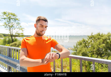 junger Mann mit intelligenten Armbanduhr am Meer Stockfoto