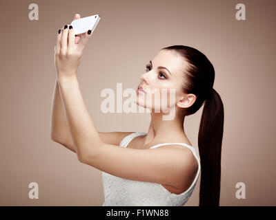 Schöne junge Frau nehmen Selfie. Mädchen, die sich mit Handy zu fotografieren. Schönheit Mode. Wimpern. Kosmetik Lidschatten Stockfoto