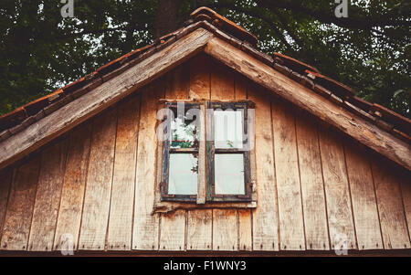 Detailansicht eines alten Holzhauses auf Fenster und Teil eines Daches. Stockfoto