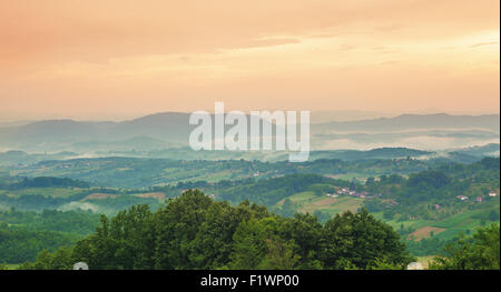 Orange Sonnenuntergang im Sommer Spätzeit, Feld, Wiesen und Wälder von einem Dorf in Serbien. Stockfoto