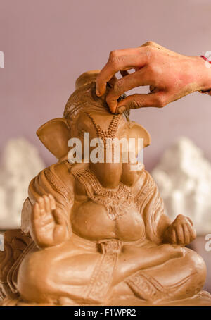 Nahaufnahme der Hand von einem Handwerker ein Idol von Lord Ganesha Ganesh Chaturthi feiern gemacht letzten Schliff verleiht. Stockfoto