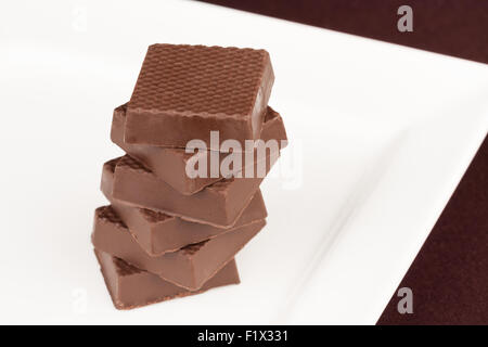 Dunkle Schokolade Quadrate übereinander auf einem weißen Tablett. Stockfoto