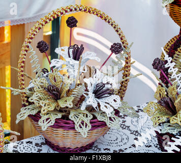Gewebt, schöne Streublumen in einem Korb auf einem Tisch mit einer Spitzen Tischdecke bedeckt. Diese Produkte zum Verkauf auf der Messe. Stockfoto