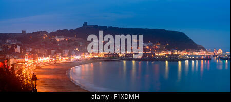 Eine genähte Panoramasicht auf Scarborough Hafen und die Burg, in der Nacht. In Scarborough, England Stockfoto