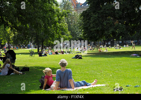 Junges Kind sitzen auf dem Rasen in einem Park mit der Mutter Stockfoto