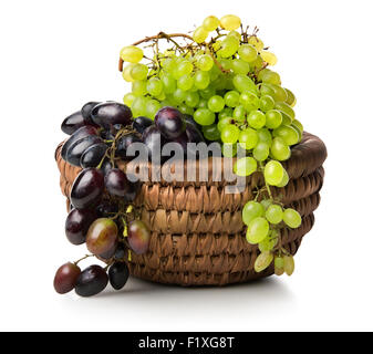 Grüne und violette Trauben in einem Korb, isoliert auf weiss Stockfoto