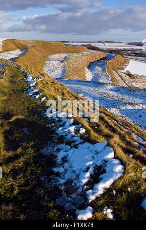 Schnee bedeckt teilweise die Eisenzeit Erde Funktionsweise von Maiden Castle in der Nähe von Dorchester in Dorset, England, UK Stockfoto