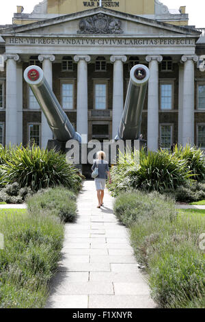 Ein Besucher bewundert die zwei Schiffsgeschütze vor dem Eingang zum Imperial War Museum in London an einem warmen sonnigen Tag Stockfoto