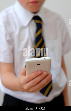 Ein Schulkind in Uniform mit seinem Mobiltelefon (SMS) UK Stockfoto