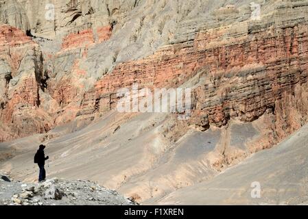 Nepal, Gandaki zone, Upper Mustang (nahe der Grenze zu Tibet), Trekker in einer mineralischen Landschaft mit roten Felsen zwischen Ghemi und Dhamkar Stockfoto