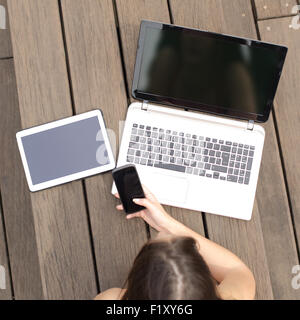 Mädchen liegend in einem Park, Job-Suche in mehreren Geräten zeigt eine leere Bildschirme Stockfoto