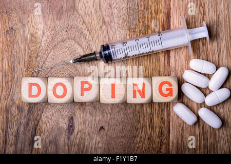 Doping, geschrieben mit Spritze und Tabletten auf Holz Stockfoto