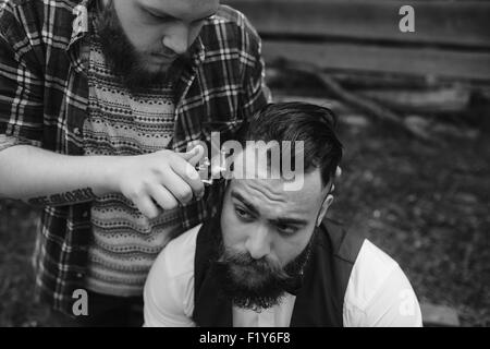 Barbier rasiert ein bärtigen Mannes Stockfoto