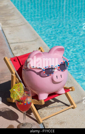 Rosa Sparschwein auf einer roten Liegestuhl entspannen ein Pool an einem heißen Sommertag mit einem Glas markiert "Prost"!  und cocktail Regenschirm Stockfoto