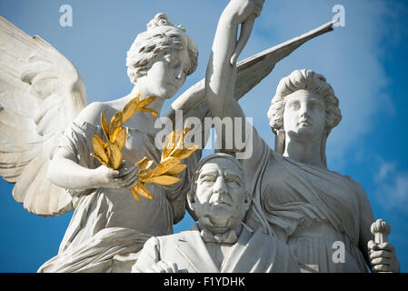 Benito Juárez Monument Alameda Central Mexico City // MEXIKO-STADT, Mexiko — das Denkmal für Benito Juárez zeigt den ehemaligen mexikanischen Präsidenten, der in der Mitte sitzt, flankiert von einer Engelsfigur und einer Darstellung des Mutterlandes. Juárez war während des 19. Jahrhunderts fünfmal Präsident und wird weithin dafür bekannt, dass er sich während der 1860er Jahre der französischen Besatzung widersetzte und Mexikos rechtliche und politische Systeme modernisierte. Das Denkmal steht im Alameda Central, dem ältesten öffentlichen Park Mexikos, im Stadtteil Centro Histórico. Die Bronzestatue wurde vom italienischen Bildhauer Lazzaro geschaffen Stockfoto