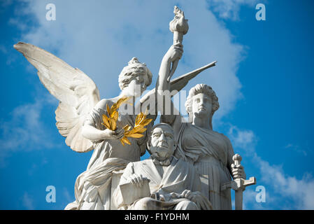 Benito Juárez Monument Alameda Central Mexico City // MEXIKO-STADT, Mexiko — das Denkmal für Benito Juárez zeigt den ehemaligen mexikanischen Präsidenten, der in der Mitte sitzt, flankiert von einer Engelsfigur und einer Darstellung des Mutterlandes. Juárez war während des 19. Jahrhunderts fünfmal Präsident und wird weithin dafür bekannt, dass er sich während der 1860er Jahre der französischen Besatzung widersetzte und Mexikos rechtliche und politische Systeme modernisierte. Das Denkmal steht im Alameda Central, dem ältesten öffentlichen Park Mexikos, im Stadtteil Centro Histórico. Die Bronzestatue wurde vom italienischen Bildhauer Lazzaro geschaffen Stockfoto