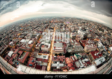 Luftbild der Skyline von Mexiko-Stadt aus Fischaugenperspektive von der Torre Latinoamericana | MEXIKO-STADT, Mexiko — Ein Fischaugen-Luftbild nach Norden vom Aussichtsdeck der Torre Latinoamericana erstreckt sich über das Raster des Centro Histórico in Richtung des beleuchteten Zócalo. Der Bezirk liegt auf dem ausgetrockneten Seegrund des Texcoco-Sees, und das unterschiedliche Absinken des weichen Tons darunter — lokal über 10 Meter (33 Fuß) — hat viele Gebäude aus der Kolonialzeit in leicht unterschiedlichen Winkeln schief stehen lassen. Stockfoto