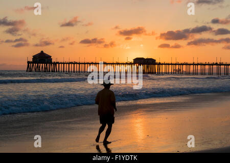 Ein Mann, Joggen am Strand von Huntington Beach Pier Kalifornien Silhouette gegen den Sonnenuntergang im Sommer Stockfoto