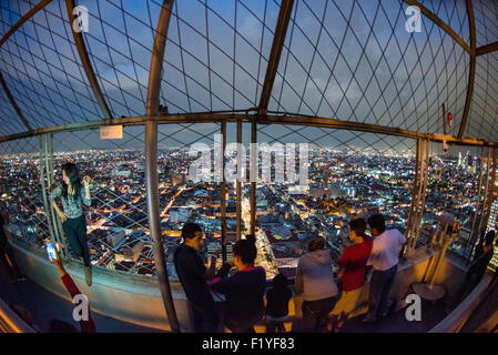 Torre Latinoamericana Observatory Mexico City // MEXICO CITY, Mexiko – Touristen bewundern den Panoramablick auf Mexiko City vom Observatorium im 44. Stock des Torre Latinoamericana Gebäudes aus. Der Torre Latinoamericana, 1956 fertiggestellt, war der erste große Wolkenkratzer von Mexiko City und bleibt eines der bekanntesten Wahrzeichen der Hauptstadt. Das 181 Meter (594 Fuß) hohe Gebäude wurde von dem Architekten Augusto H. Álvarez entworfen und diente mehrere Jahre lang als das höchste Gebäude Lateinamerikas. Die Aussichtsplattform des Turms bietet einen atemberaubenden Blick über die weitläufige Metropole Stockfoto