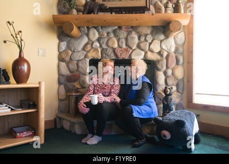 Zwei glückliche Blondine kaukasischen Frauen sitzen auf einem Kamin Felsvorsprung Lachen im Gespräch Stockfoto