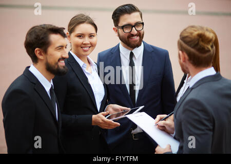 Glücklich Geschäftsfrau Blick in die Kamera während Gespräch mit Kollegen Stockfoto