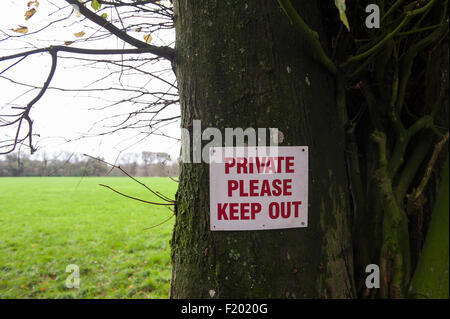 "Private Bitte halten" Abmelden in rot auf weiß an einem Baum neben einer Wiese genagelt. Dorset, England. Stockfoto