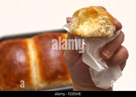 Damen Hand hält eine gebutterte Portion hausgemachtes Brot über ein gebackenes Brot in den Boden zurück Stockfoto