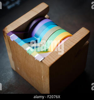 Eine hölzerne Scotch Tape Dispenser mit vielen farbigen Bändern. Stockfoto