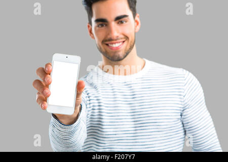 Hübscher junger Mann zeigen etwas auf seinem Handy, über grauen Hintergrund isoliert Stockfoto