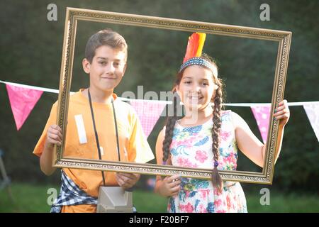 Jungen und Mädchen durch Bilderrahmen, Lächeln, Blick in die Kamera Stockfoto