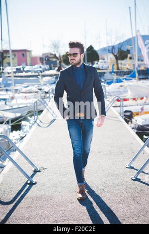 Junger Mann mit Hand in der Tasche gehen auf See pier Stockfoto