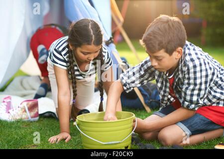 Junge und Schwester Lagerfeuer im Garten Eimer vorbereiten Stockfoto