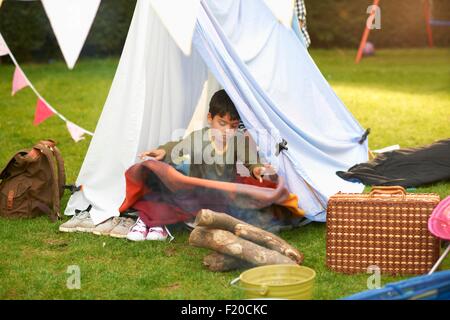 Junge schütteln Decke aus hausgemachten Zelt im Garten Stockfoto