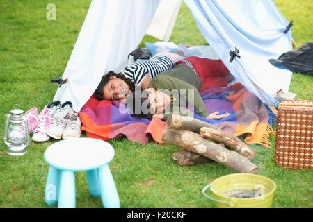 Bruder und Schwester liegen in hausgemachten Zelt im Garten Stockfoto