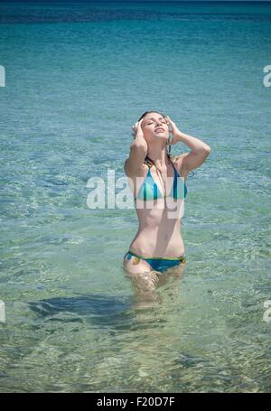 Junge Frau trägt Bikini mit Händen in Haaren im Meer, Cagliari, Sardinien, Italien Stockfoto