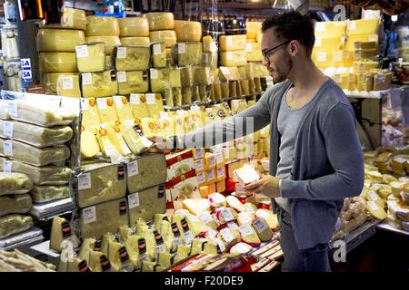 Junger Mann, die Auswahl von Käse in Feinkost Marktstand, Sao Paulo, Brasilien