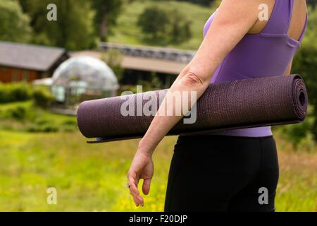 Blick auf Reife Frau, die Yoga-Matte in Eco Lodge Bereich beschnitten Stockfoto